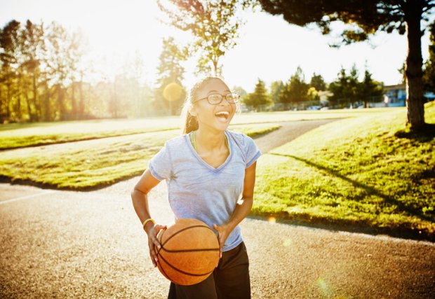 A teen girl holding a basketball