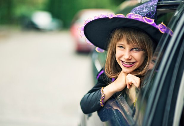 A little girl in a car, dressed up like a witch for halloween